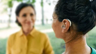 woman talking with friend wears behind the ear hearing aid