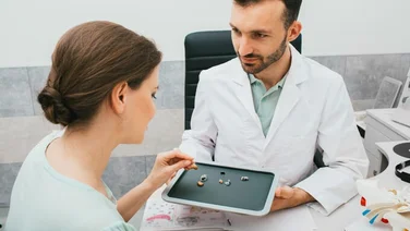 pharmacist shows lady different types of hearing aids